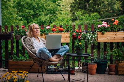 Personne sur une terrasse entourée de compositions florales en été.